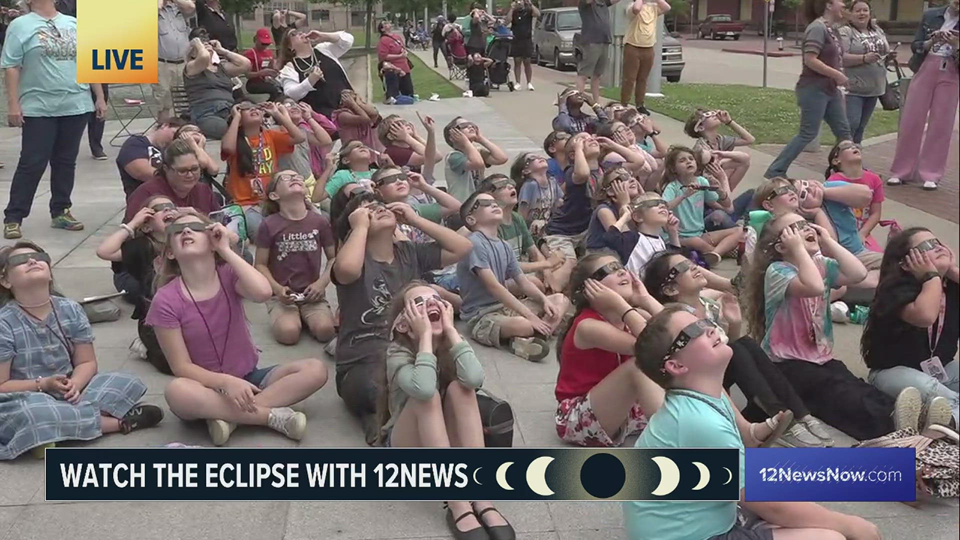 A small crowd including young school children react as they watch the approach of the peak of the eclipse Monday at the Beaumont Event Centre.
